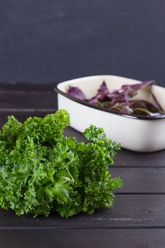 Fresh basil greens, parsley on a black background. Dark rustic style.