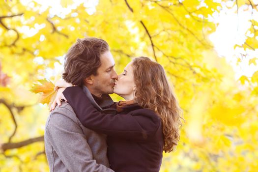 Love, relationship, family and people concept - couple kissing in autumn park