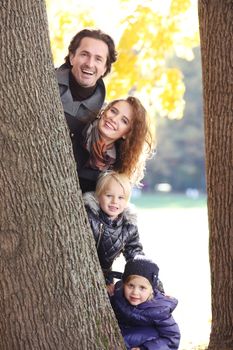 Happy family with two children looking out from a tree walking in a forest