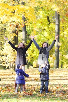 Happy family playing with autumn maple leaves in park