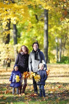 Happy family with two children walking in autumn park holding hands