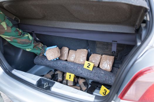 Policeman holding drug package discovered in the trunk of a car