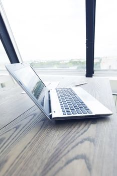 Office workplace with laptop and document on wood table against the window