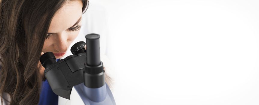 Female doctor looking through a microscope, studio shot isolated on white background
