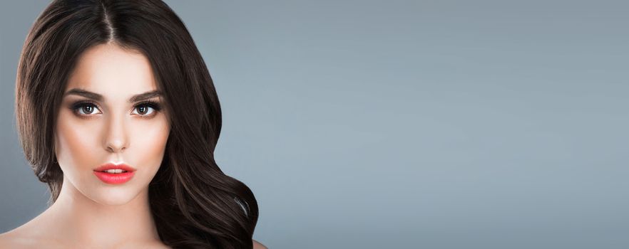 Beauty studio portrait of brunette woman with natural make-up over gray background