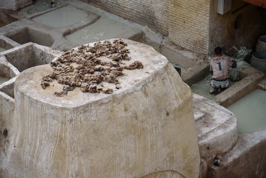 Men working in the Chouara Tannery in the middle of souk in Fez, Morocco. Traditional leather tannery from  the 11th century is now biggest tourits attraction in Fes.