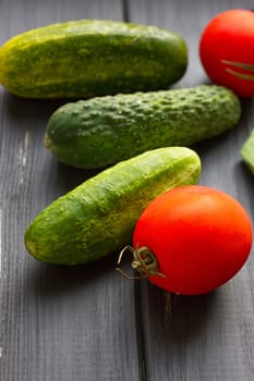 Tomatoes and cucumber on the black wood background