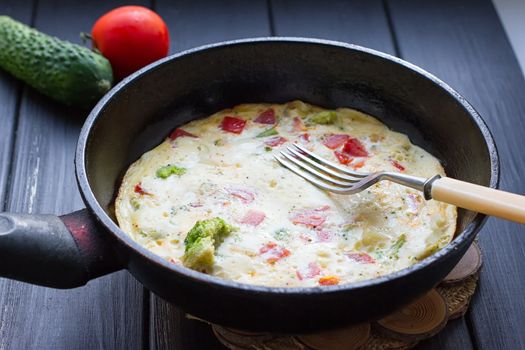 Breakfast set. Pan of fried eggs with fresh tomato, cucumber, sage on dark serving board over black background