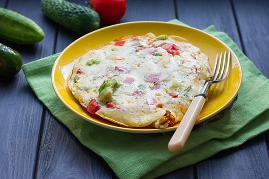 Hearty and tasty breakfast, traditional in the hotel, omelette from chicken eggs with cheese, fresh vegetables - cucumber and tomato on the black wooden background