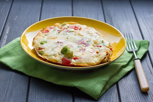 Hearty and tasty breakfast, traditional in the hotel, omelette from chicken eggs with cheese, fresh vegetables - cucumber and tomato on the black wooden background