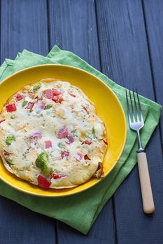 Hearty and tasty breakfast, traditional in the hotel, omelette from chicken eggs with cheese, fresh vegetables - cucumber and tomato on the black wooden background