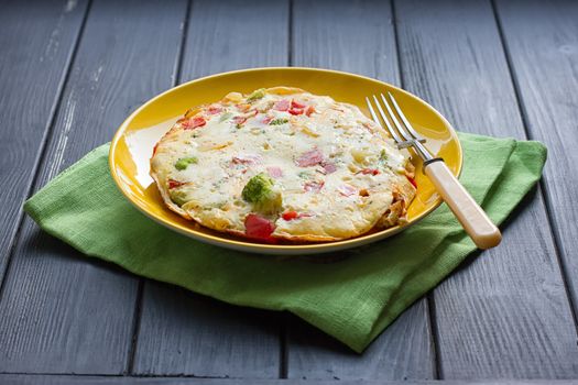 Hearty and tasty breakfast, traditional in the hotel, omelette from chicken eggs with cheese, fresh vegetables - cucumber and tomato on the black wooden background