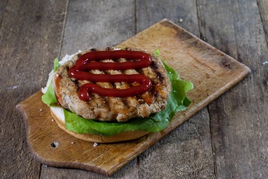 Roll with roast cutlet. Hamburger on a wooden board. Kitchen table, black background.