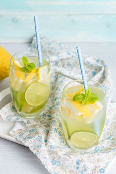 Summer citrus fruits drink on wooden background. Detox citrus infused flavored water. Refreshing summer homemade cocktail with lemon. Fresh lemon and lemonade on wooden background