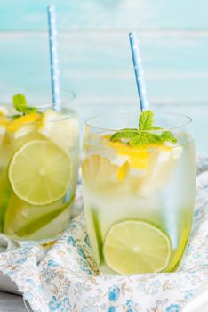 Summer citrus fruits drink on wooden background. Detox citrus infused flavored water. Refreshing summer homemade cocktail with lemon. Fresh lemon and lemonade on wooden background