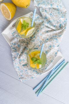 Summer citrus fruits drink on wooden background. Detox citrus infused flavored water. Refreshing summer homemade cocktail with lemon. Fresh lemon and lemonade on wooden background