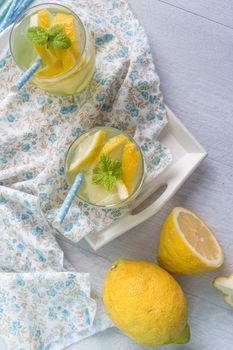 Summer citrus fruits drink on wooden background. Detox citrus infused flavored water. Refreshing summer homemade cocktail with lemon. Fresh lemon and lemonade on wooden background