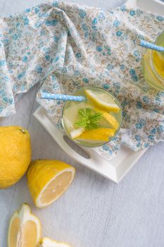 Summer citrus fruits drink on wooden background. Detox citrus infused flavored water. Refreshing summer homemade cocktail with lemon. Fresh lemon and lemonade on wooden background