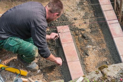 Workers in advance for laying paving stones and bricks. Various tools in the background.