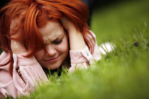 Portrait of the girl with red hair in a grass