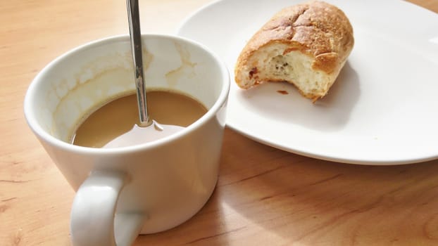 Breakfast with coffee and fresh croissant on a white plate.