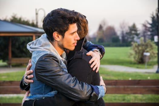 Portrait of cheerful and handsome man hugging his best friend and looking away outdoor