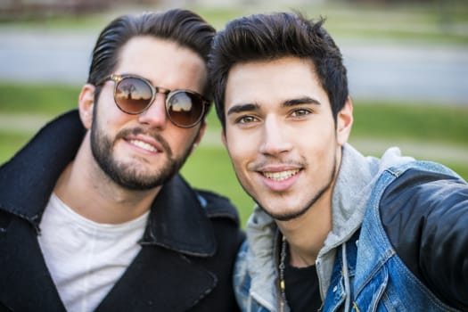 Two young men taking selfie while outdoors, point of view of the camera itself