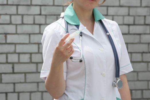 Medicine concept doctor. graft. On a white brick wall background. Holds a syringe with a needle. Photo for your design