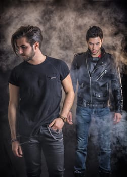 Two attractive young hard rock men posing in studio. Black background