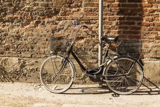 Old bicycle parked on a building wall in Ravenna, Italy