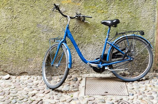 Old bicycle parked on a building wall in Ravenna, Italy