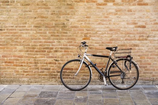Old bicycle parked on a building wall in Ravenna, Italy