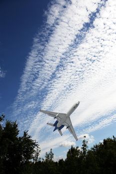 Closeup of passenger airplane take-off above forest against sky with clouds 
