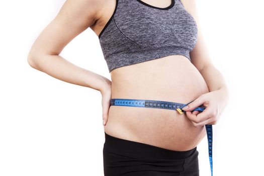 Pregnant woman measures her belly with a measure.