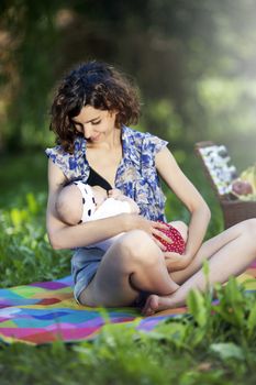 Young beautiful mother sits on blanket with her daughter during a picnic in the park