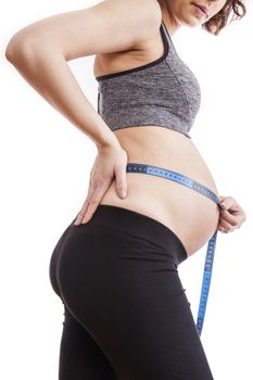 Pregnant woman measures her belly with a measure.