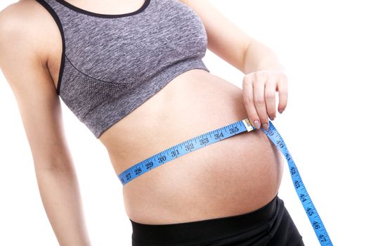 Pregnant woman measures her belly with a measure.