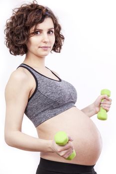 Young pregnant woman practicing fitness. Isolated on white background