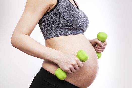 Young pregnant woman practicing fitness. Isolated on white background