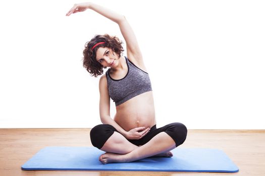 young pregnant woman exercises on the mat. Isolated shot