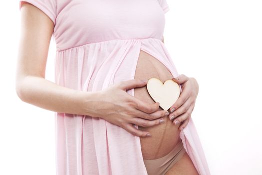 Pregnant woman puts heart on her belly.