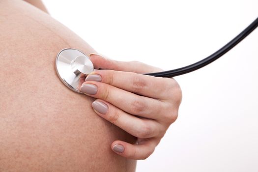 Pregnant woman listens to her child through a stethoscope.