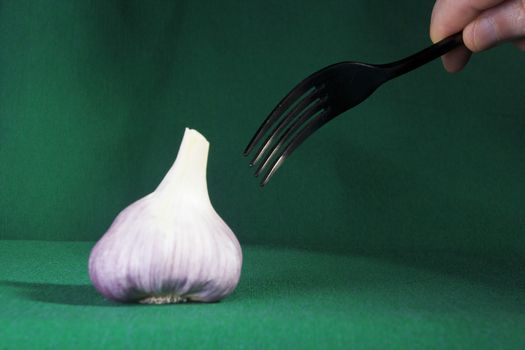 Fork and garlic on a green background