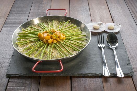 Paella with scollops and asparagus in traditional pan.