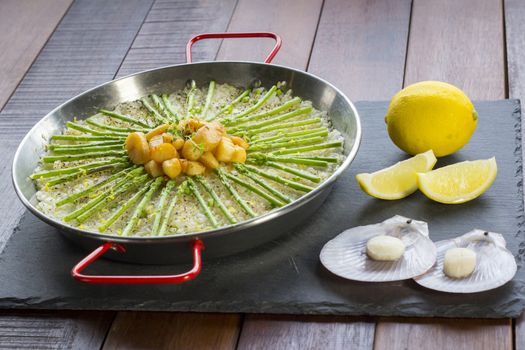 Paella with scollops and asparagus in traditional pan.