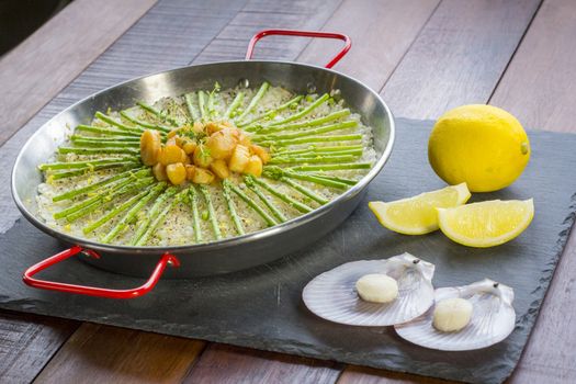 Paella with scollops and asparagus in traditional pan.