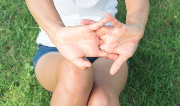 Closeup woman stretching exercises finger in the park with sun light, selective focus