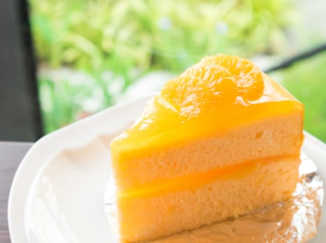 Closeup orange cake on wood table with nature background