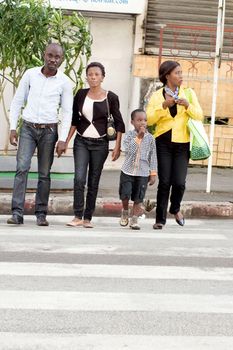 family aligned across the road by the white stripes  of  traffic lights.
