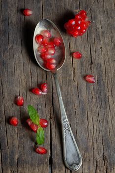 Ripe pomegranate and spoon on wooden table